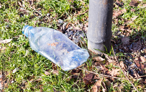 Shredded plastic mineral water bottles and bottle caps on the grass in the park, the concept of environmental protection, environmental protection clogging