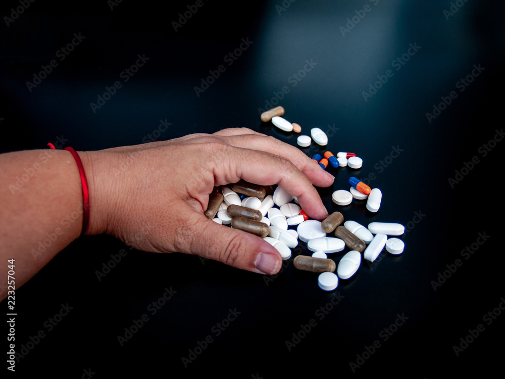 A person holding pills of different sizes, shapes and colors with his hand. Health concept