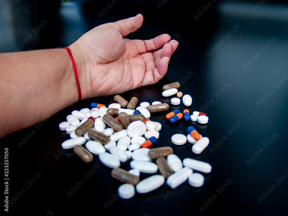 A person holding pills of different sizes, shapes and colors with his hand. Health concept A person holding pills of different sizes, shapes and colors with his hand. Health concept