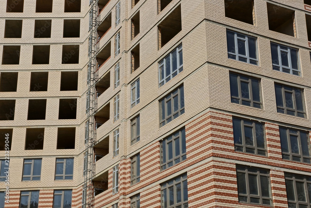 a texture of many windows on the brown wall of an unfinished building