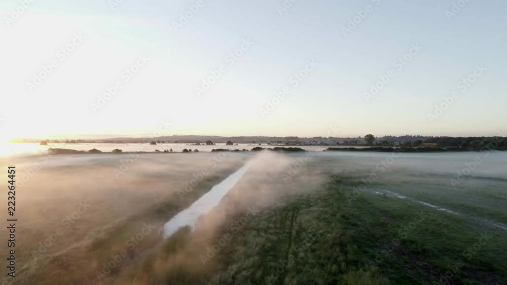 Panning left with a view over a river and a misty field in bright sunlight. Panning left with a view over a river and a misty field in bright sunlight.