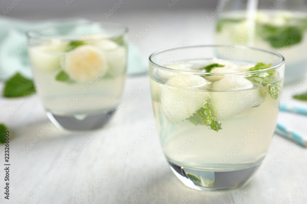 Glass with tasty melon ball drink on light table Glass with tasty melon ball drink on light table