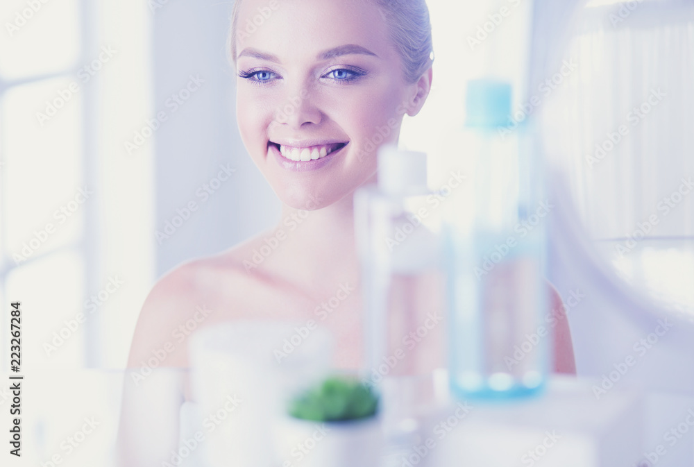Young woman in bathrobe looking in bathroom mirror Young woman in bathrobe looking in bathroom mirror