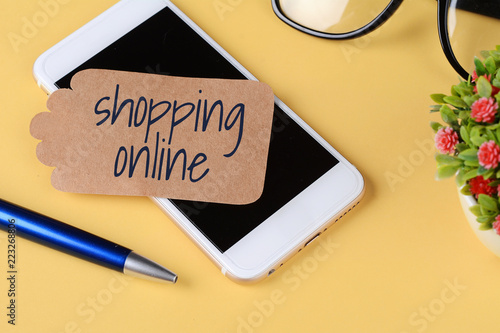 Paper card with "shoping online" text and pen, glasses with phone