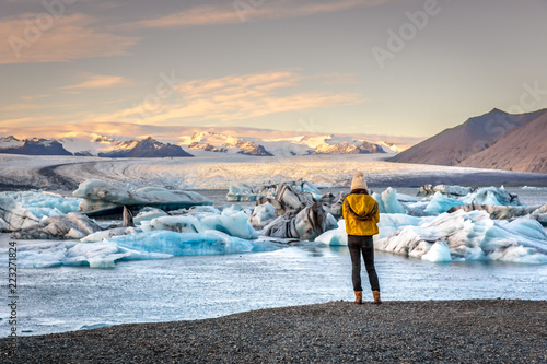 Young woman dressing cold clothes seeing the amazing Jokulsarlon, iceberg lagoon in Iceland photo