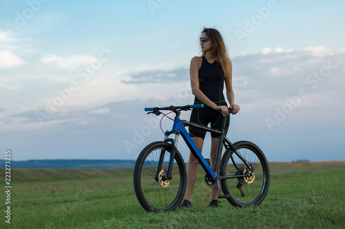 Girl on a mountain bike on offroad, beautiful portrait of a cyclist at sunset 