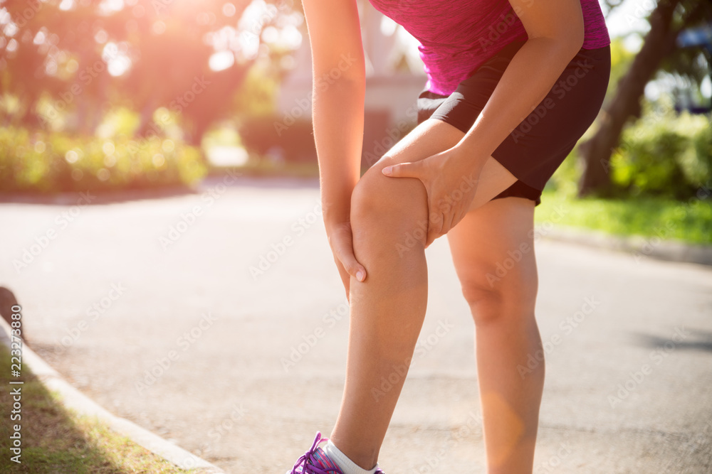 Runner sport knee injury. Woman in knee pain while running in the garden.