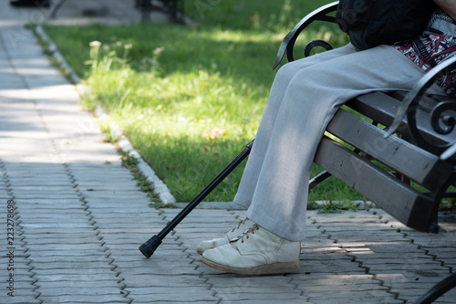 Fotografija On the image of a foot, a crutch and a bench in the park