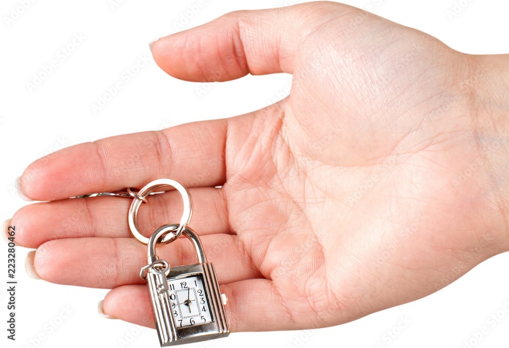 Female hand holding keychain with little clock and key isolated Female hand holding keychain with little clock and key isolated