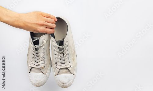 White dirty sneaker shoes with hand holding on white background