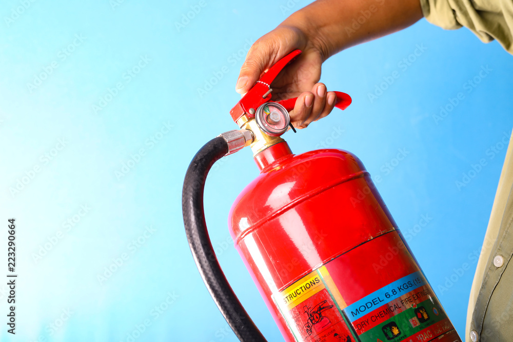 Naklejka premium A man holding fire extinguisher on blue background.