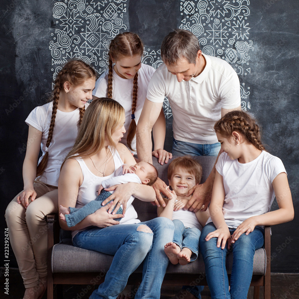 Big family portrait.  Parents plaing with five children. Mother and father with newborn baby, toddler and teenagers. Concept of big happy family