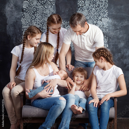 Big family portrait. Parents plaing with five children. Mother and father with newborn baby, toddler and teenagers. Concept of big happy family