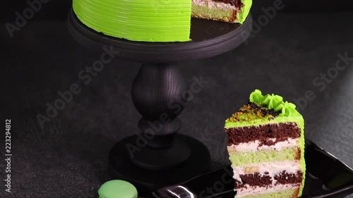 Fresh pistachio cake with a cut piece over dark background