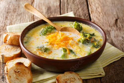 Traditional recipe of broccoli cheese soup with vegetables in a bowl with toast close-up. horizontal