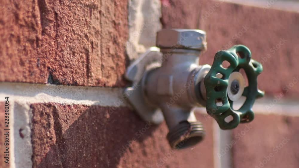 Green faucet head close up attached to brick wall Green faucet head close up attached to brick wall