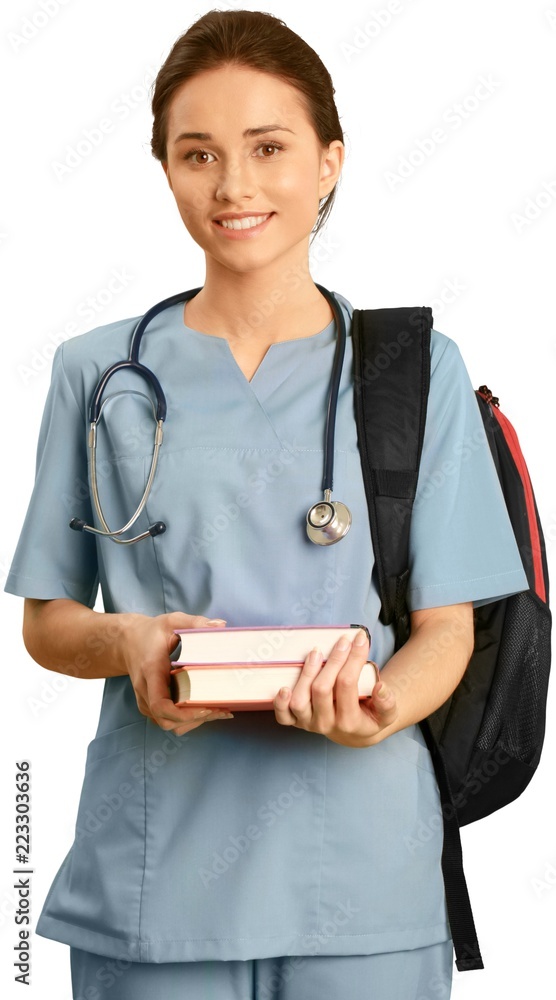Female healthcare worker wearing scrubs and carrying textbooks Female healthcare worker wearing scrubs and carrying textbooks