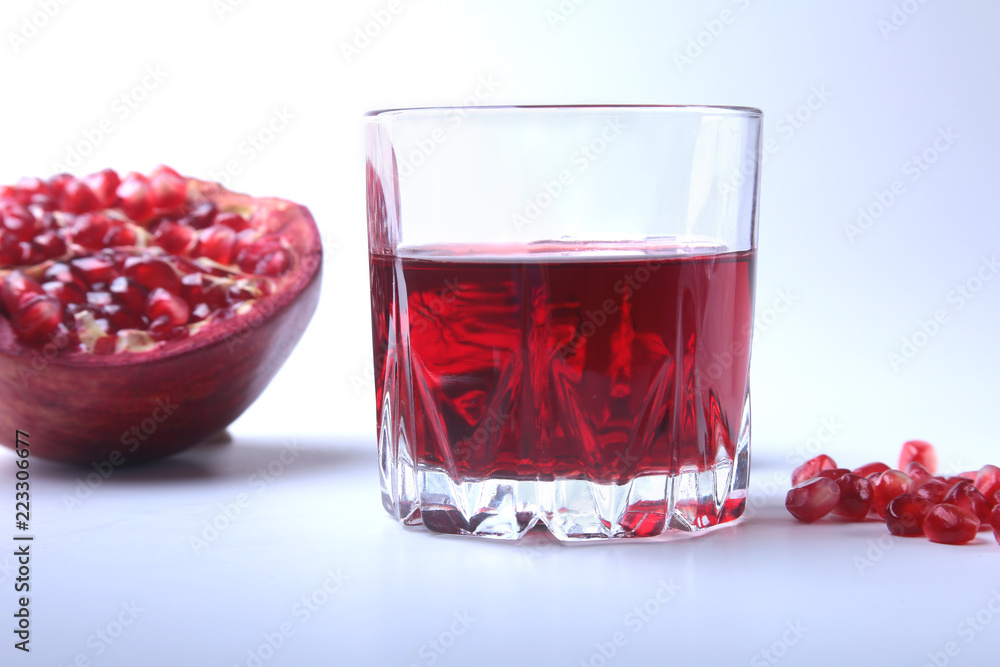 Glass with pomegranate juice Pomegranate seeds and Beautiful ripe pomegranate on white background with place for copy space. Glass with pomegranate juice Pomegranate seeds and Beautiful ripe pomegranate on white background with place for copy space.
