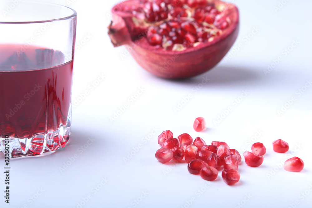 Glass with pomegranate juice Pomegranate seeds and Beautiful ripe pomegranate on white background with place for copy space. Glass with pomegranate juice Pomegranate seeds and Beautiful ripe pomegranate on white background with place for copy space.
