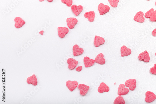 Many pink sugar hearts are scattered on a light background