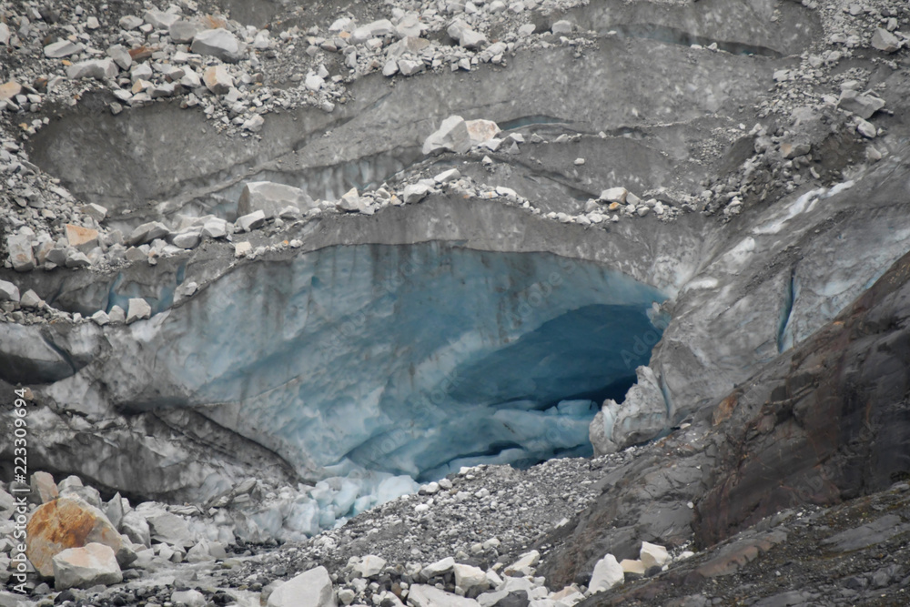 Turquoise blue glacial cave in Glacier Bay, Alaska with black debris from the moraine