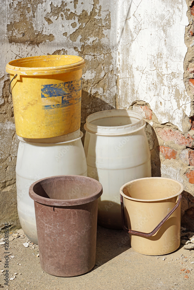 Plastic barrels and buckets next to a wall Plastic barrels and buckets next to a wall