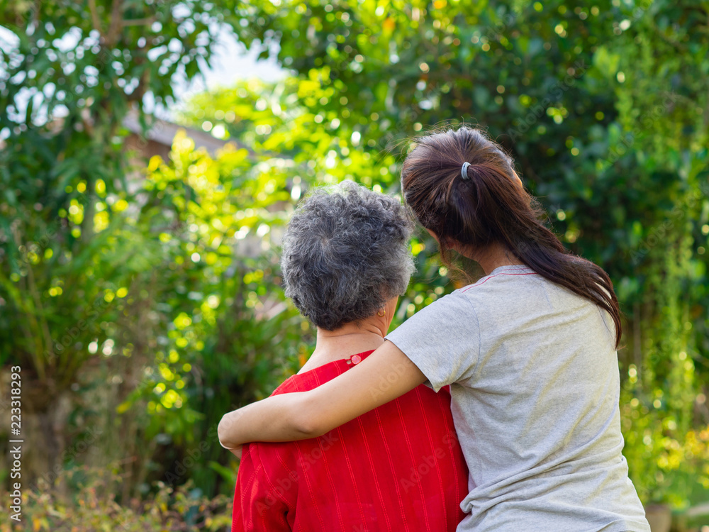 Back view of young woman hugging her grandmother in garden. Back view of young woman hugging her grandmother in garden.