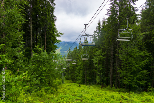 Ski lift in the rainy summer mountains through amazing fabulous moutain forest in Bukovel, Ukrainian Carpathians