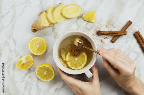 Fotografia Flatlay of healthy drink with lemon, fresh ginger root, cinnamon sticks and agav