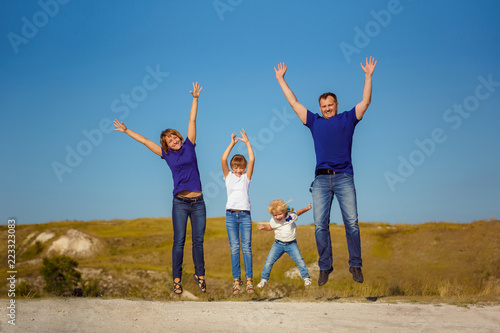 happy family is fooling around in nature and bouncing against a blue sky.