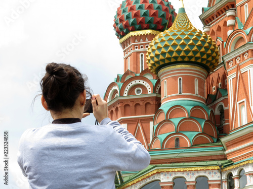 Woman tourist taking pictures with smartphone the St. Basil's cathedral on Red square in Moscow. Tourism in Russia, russian landmarks and symbols