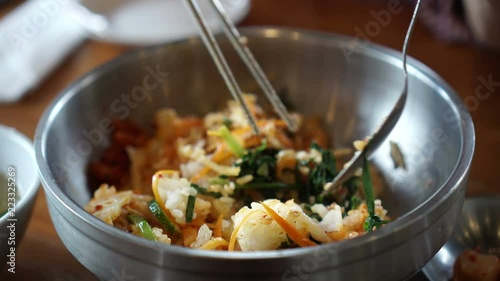 Hand using chopstick and spoon mixing bibimbap Korean iconic food dish