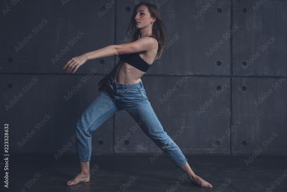 young beautiful woman in top and jeans dancing modern contemporary dance in the studio, contemporary art, harmony of body and soul, professional dancer