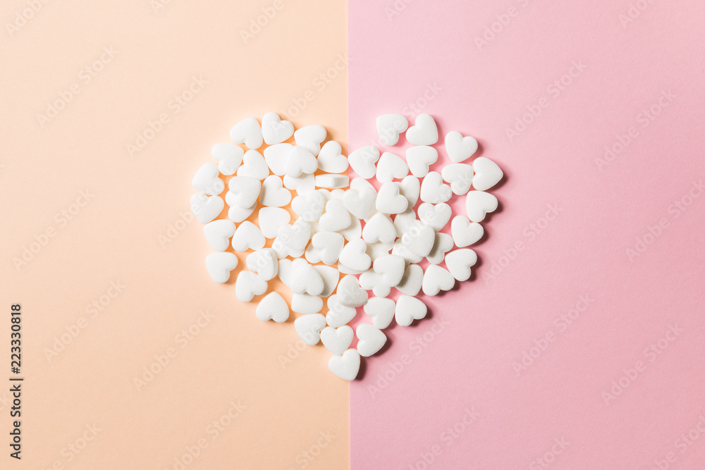 Tablets in the form of hearts on a double pink and solid background.