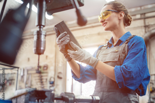 Woman in metal workshop checking workpiece for accuracy  photo