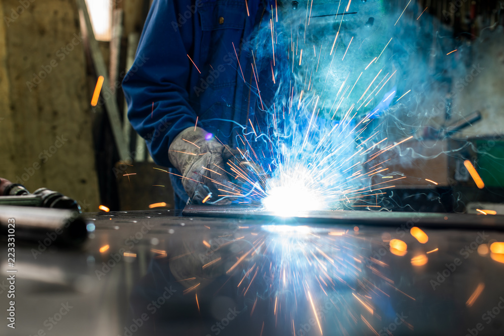 Welder in his workshop welding metal, lots of sparks flying around Welder in his workshop welding metal, lots of sparks flying around