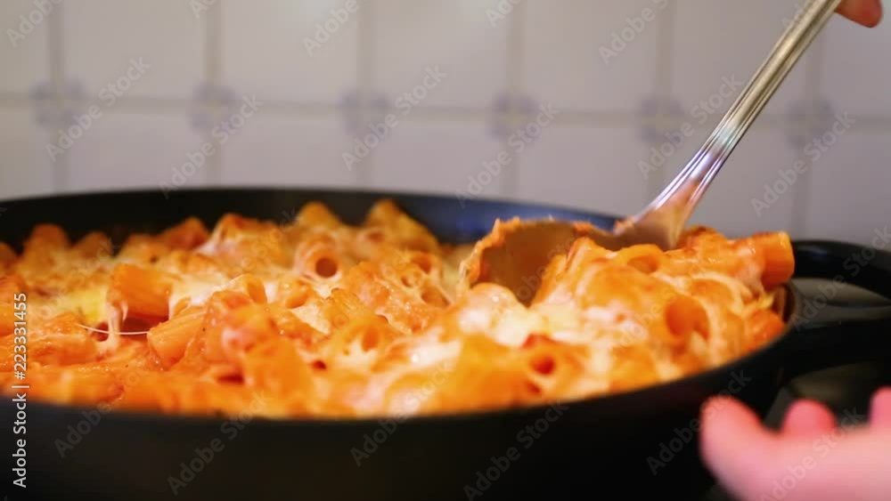 Baked rigatoni scooped out of pan with lots of mozzarella melted on top