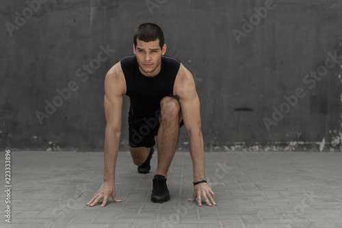 Sportsman starting his sprint on a gray industrial wall backgrou © arthurhidden