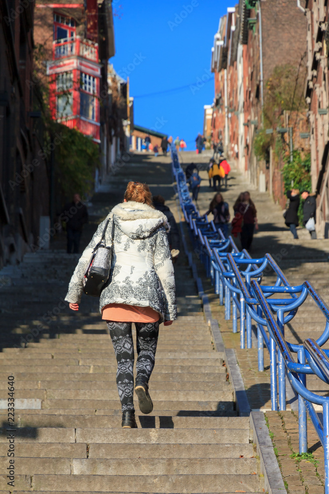 Beautiful young woman climbs the 374-step long staircase Montagne de Bueren, a popular landmark and tourist attraction in Liege, Belgium