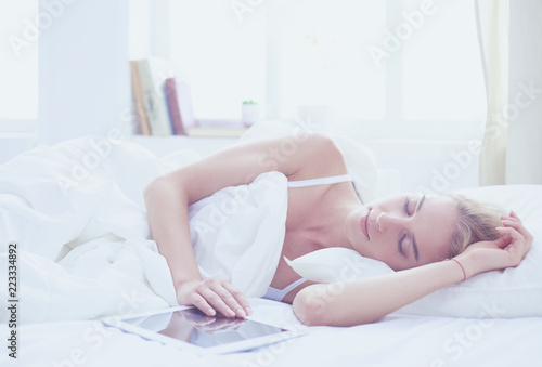 Girl holding digital tablet with blank screen and smiling at camera in bedroom