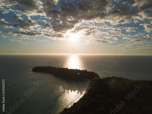 Aerial view of a magnificent sunset landscape: an island with white beach, crystal clear sea, palm trees. Wonderful places for a dream vacation. Concept of: holiday, wild, nature.