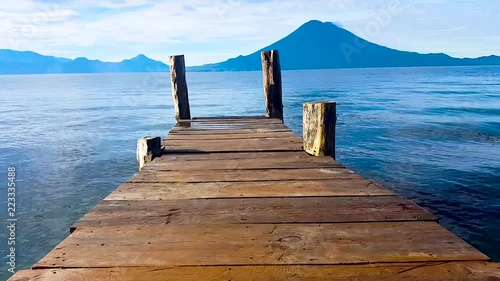 Walking on the bridge seeing the landscape of Amatitlan lake and a beautiful volcano in a sunny day with blue sky and montains. photo