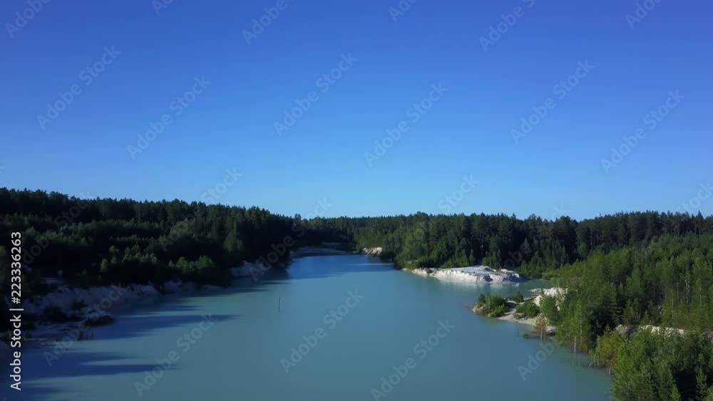 Aerial epic drone flight to the abandoned kaolin quarry over the turquoise water through the branches pine tree, flight to the horizon, sunny evening in anthropogenic landscape of South Ural, Russia Aerial epic drone flight to the abandoned kaolin quarry over the turquoise water through the branches pine tree, flight to the horizon, sunny evening in anthropogenic landscape of South Ural, Russia
