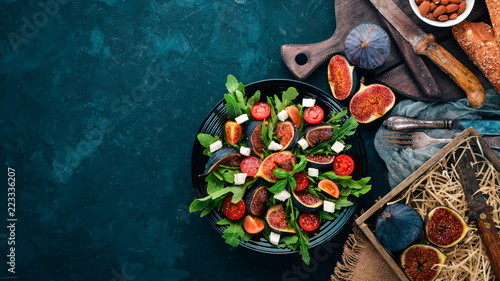 Fresh salad with figs, arugula leaves, cherry tomatoes and feta cheese. Free space for text. Top view.