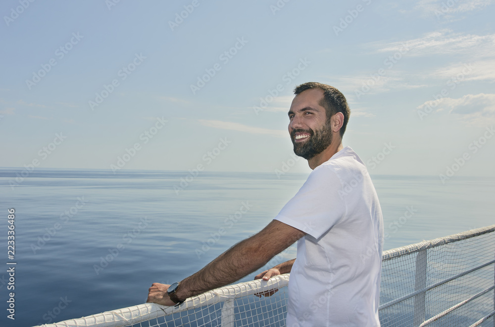 Handsome man smiling on the deck of a ship during holidays.