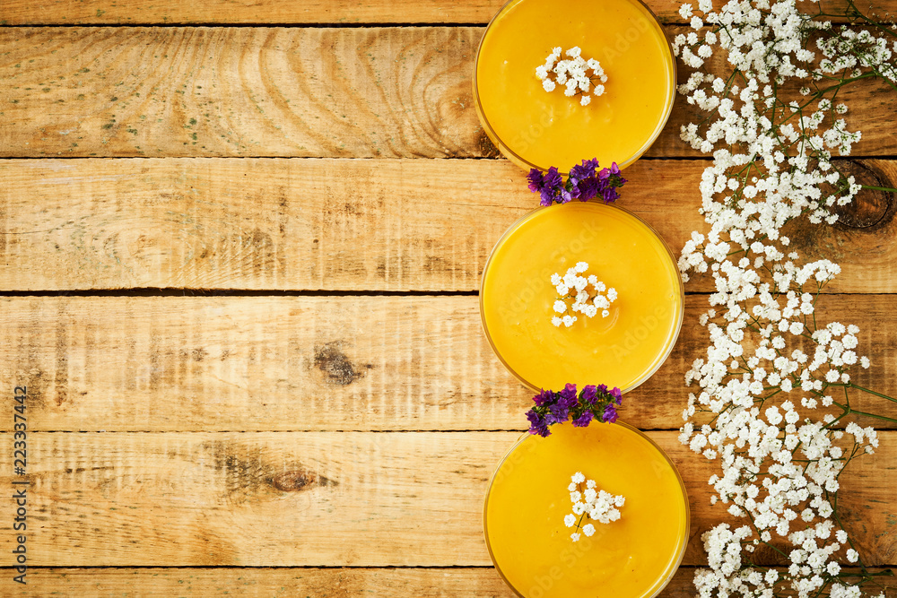 fresh and delicious pumpkin soup and flowers on an old wooden kitchen table fresh and delicious pumpkin soup and flowers on an old wooden kitchen table