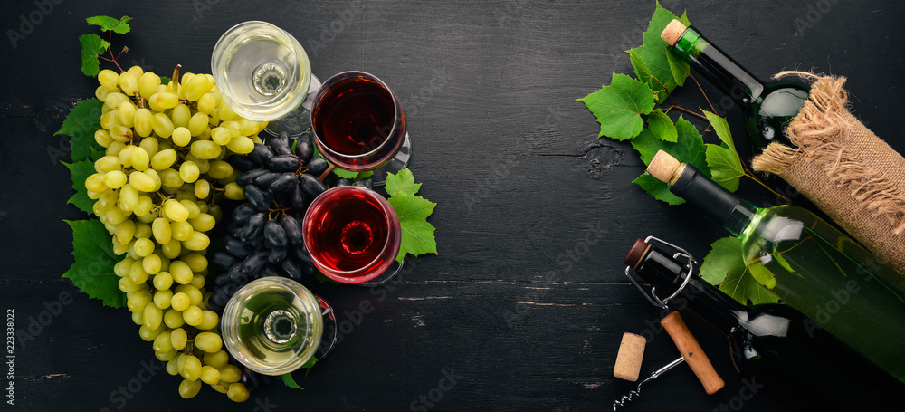 Set of red and white wine in bottles and glasses. Grape. On a black wooden background. Free space for text. Top view. Set of red and white wine in bottles and glasses. Grape. On a black wooden background. Free space for text. Top view.