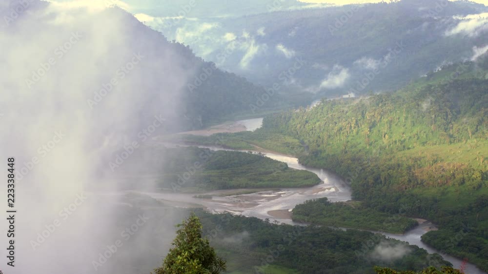 The Rio Abanico Valley, Ecuador, with misty cloudforest covered hillsides. Farmsteads cleared from forest illuminated by evening sun.  On the Amazonian slopes of the Andes in Morona Santiago province