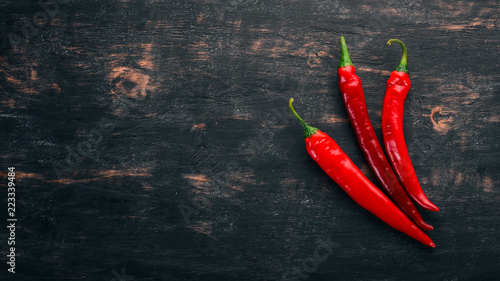 Chili red pepper. On a black wooden background. Free space for text. Top view.
