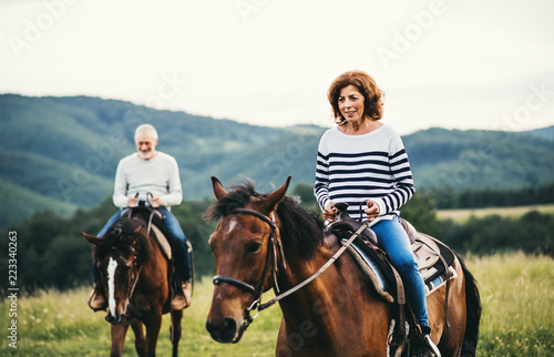 A senior couple riding horses in nature. © Halfpoint